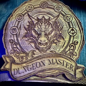 May include: A wooden plaque with a dragon design and the text "Dungeon Master" in a banner. The dragon is surrounded by a circle of dice.