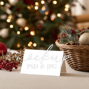May include: A white card with the word "mockup" and "PSD & JPG" in a festive setting. A Christmas tree with golden ornaments and lights is in the background. A woven basket with holiday decor is on the right.