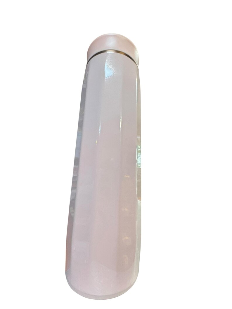 Peut inclure: Une gourde isotherme rose p&acirc;le, mince, avec un bord et un bouchon argent&eacute;s m&eacute;talliques. La bouteille a une finition lisse et brillante et une base arrondie. Le bouchon est de couleur rose p&acirc;le assortie.