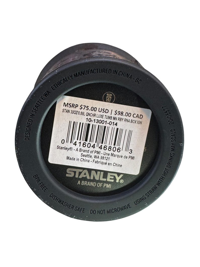 May include: Black Stanley tumbler with a white label displaying product information. The label includes the text "STANLEY" and "A BRAND OF PMI". The bottom of the tumbler has the text "BPA FREE DISHWASHER SAFE DO NOT MICROWAVE".
