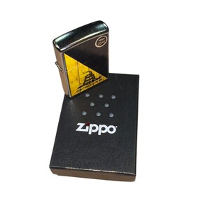 Puede incluir: Un encendedor Zippo con un dise&ntilde;o negro y amarillo con la frase "DON'T TREAD ON ME". El encendedor est&aacute; encima de su caja negra, que tiene el logotipo de Zippo impreso.