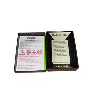 Puede incluir: Dos cajas de encendedores Zippo abiertas. Una caja muestra advertencias de seguridad y el texto "Genuine Zippo Windproof Lighter". La otra caja dice "Made in USA" e incluye el logotipo de Zippo e informaci&oacute;n del sitio web.