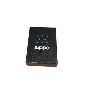 Puede incluir: Una caja rectangular negra con la marca "Zippo" en blanco. La caja tiene un patr&oacute;n de puntos en la parte superior. La caja es probablemente para un encendedor o un producto similar.