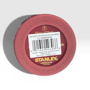 May include: A maroon-colored Stanley mug base with product information. The mug is 16oz / 473ml, dishwasher safe, and BPA free. The text includes "Designed in Seattle, WA" and "Ethically Manufactured in China."