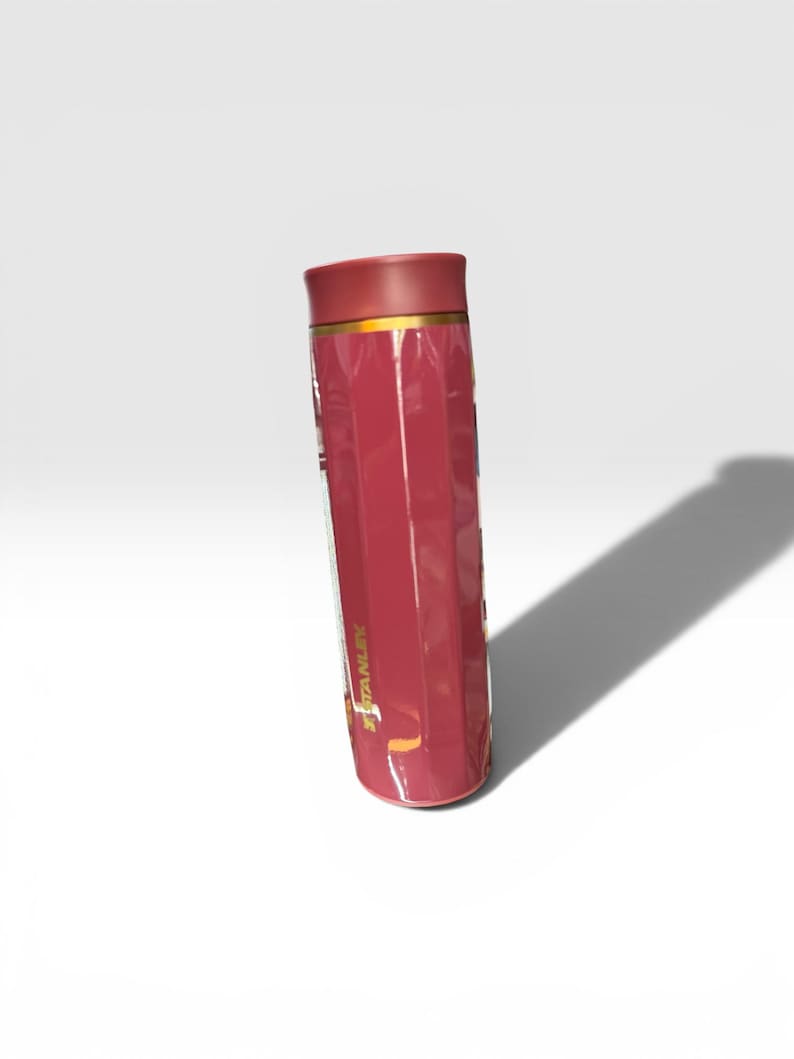 May include: A maroon Stanley thermos with a gold band near the top. The thermos has a ridged design and a maroon lid. The Stanley logo is visible on the side of the thermos.