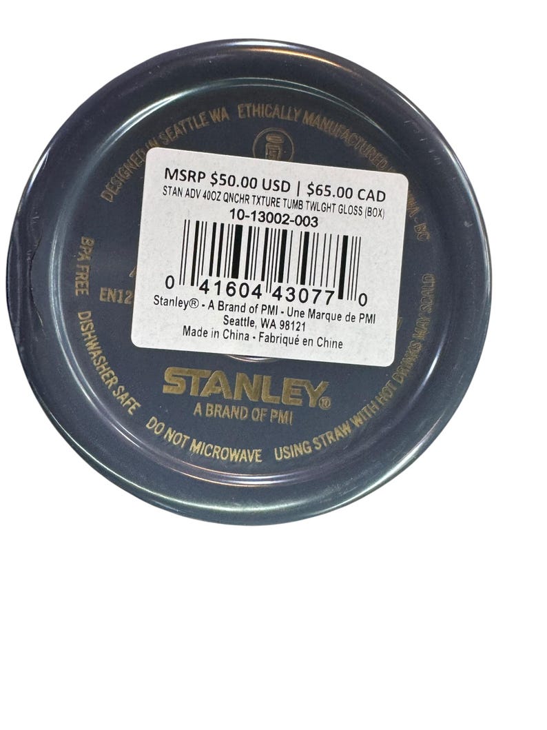 May include: A dark blue Stanley tumbler with a textured finish. The product label includes the text "STAN ADV 40OZ QNCHR TXTURE TUMB TWLGHT GLOSS (BOX)" and "BPA FREE". The tumbler is designed in Seattle, WA, and is dishwasher safe.