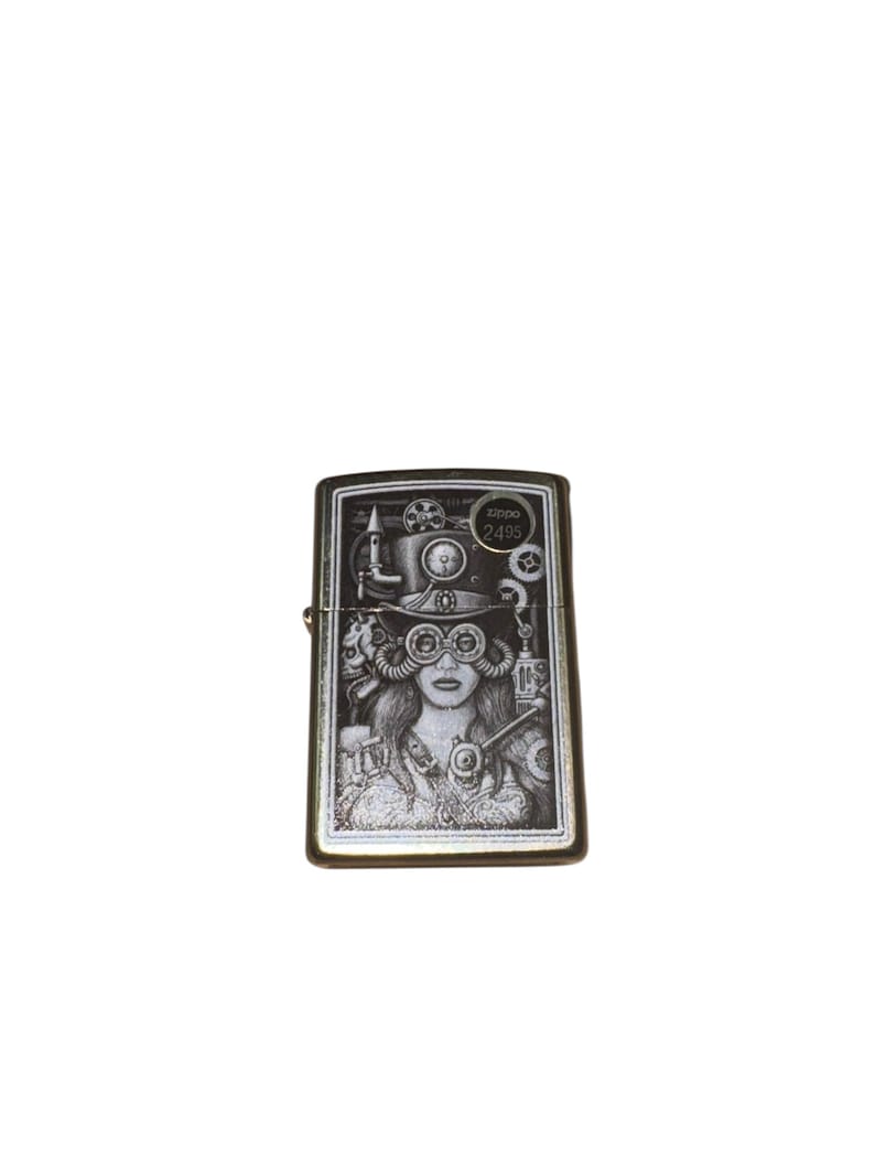 Puede incluir: Un encendedor Zippo plateado con una ilustraci&oacute;n en blanco y negro de una mujer con atuendo steampunk. El dise&ntilde;o incluye un sombrero de copa, gafas y elementos mec&aacute;nicos. El texto "Zippo 2495" es visible.
