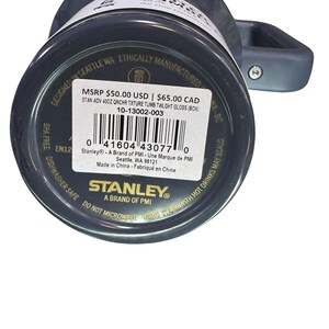 May include: A dark gray Stanley 40oz tumbler with a handle. The bottom of the tumbler has a product label with the brand name and product information. The tumbler is designed in Seattle, WA.