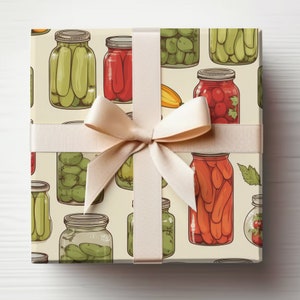 May include: A gift box wrapped in cream paper with a beige ribbon. The paper features a repeating pattern of various jars filled with pickled vegetables, peppers, and tomatoes.