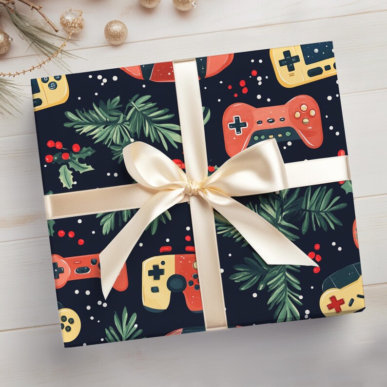K&ouml;nnte beinhalten: Ein Geschenk, verpackt in marineblauem Papier mit einem Muster aus Videospiel-Controllern, Stechpalmen und Tannenzweigen. Es ist mit einem cremefarbenen Band und einer Schleife gebunden, ideal f&uuml;r ein Weihnachtsgeschenk f&uuml;r Gamer.