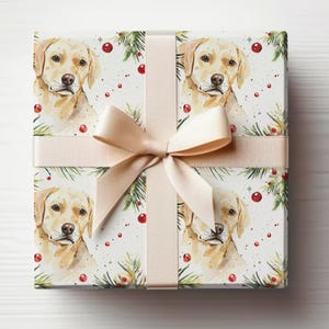 May include: Gift-wrapped present featuring a watercolor design of a golden Labrador Retriever. The wrapping paper has a repeating pattern of the dog's portrait, pine needles, and red berries. A beige ribbon and bow complete the festive look.