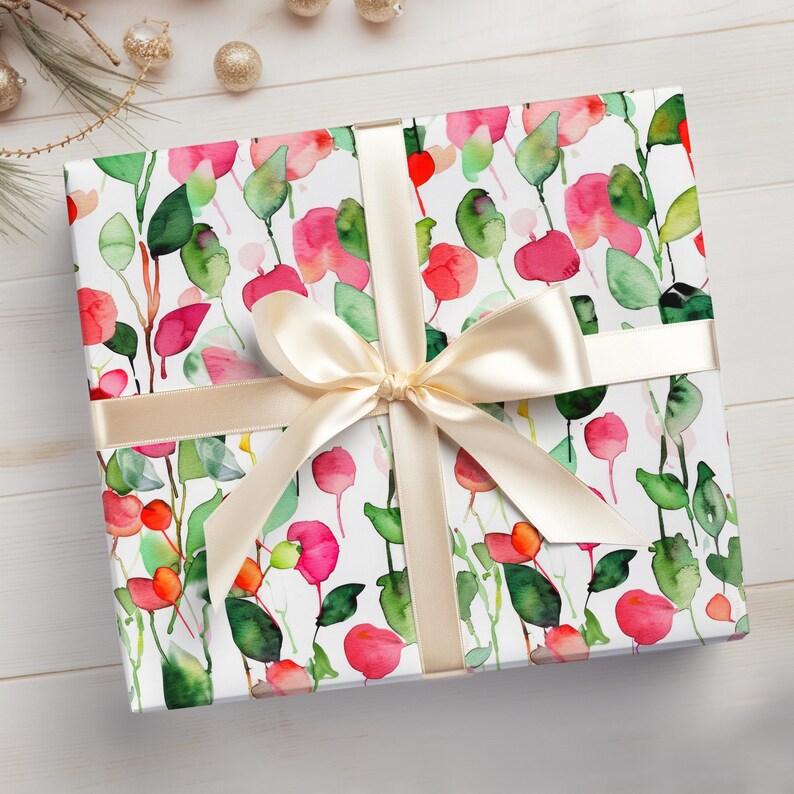 May include: A white gift box with a floral pattern in shades of pink, green, and white. The box is tied with a cream-colored satin ribbon.