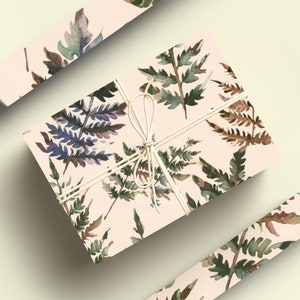 May include: A gift box wrapped in pink wrapping paper with a watercolor fern pattern. The box is tied with twine and has a bow.