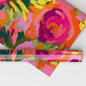 May include: A roll of colorful wrapping paper with a floral pattern. The paper features a bright pink, orange, yellow, and green abstract floral design.