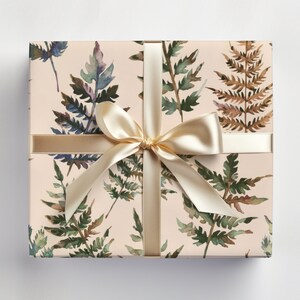 May include: A gift box wrapped in beige paper with a watercolor fern pattern. The box is tied with a cream-colored satin ribbon.