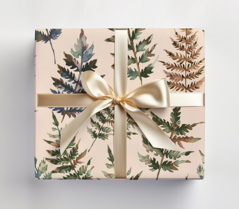 May include: A gift box wrapped in beige paper with a watercolor fern pattern. The box is tied with a cream-colored satin ribbon.
