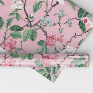 May include: Pink floral wallpaper featuring roses, leaves, and branches. The design includes white, pink, and red roses with green leaves and brown branches. A roll of wallpaper is visible, along with a folded section.
