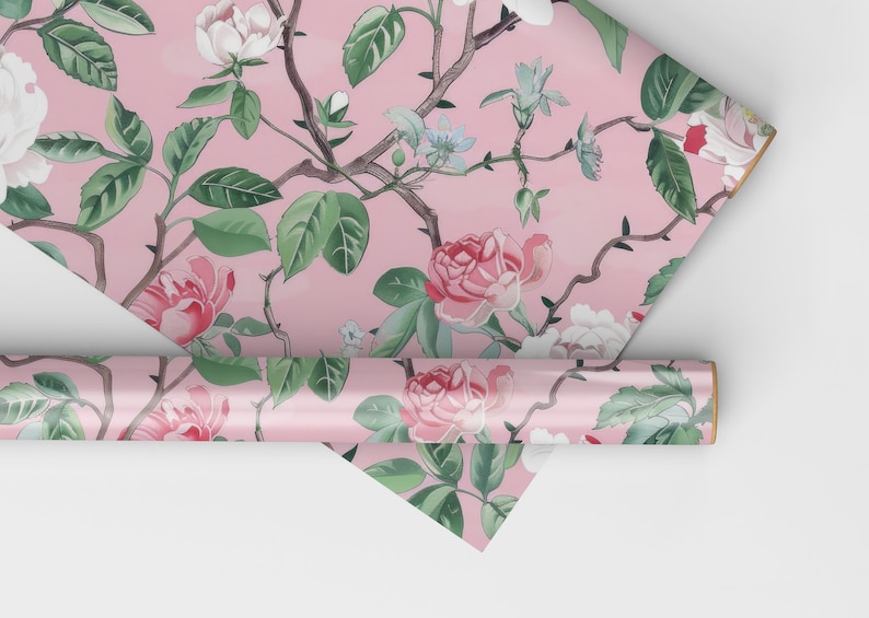 May include: Pink floral wallpaper featuring roses, leaves, and branches. The design includes white, pink, and red roses with green leaves and brown branches. A roll of wallpaper is visible, along with a folded section.