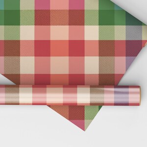 May include: A roll of colorful plaid wrapping paper with a variety of colors including red, green, and beige. The paper is unrolled to reveal the plaid pattern. A smaller roll of the same paper is also visible.