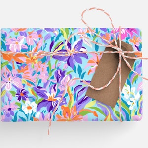 May include: A gift box wrapped in blue floral patterned paper with a brown gift tag tied with pink and white twine.