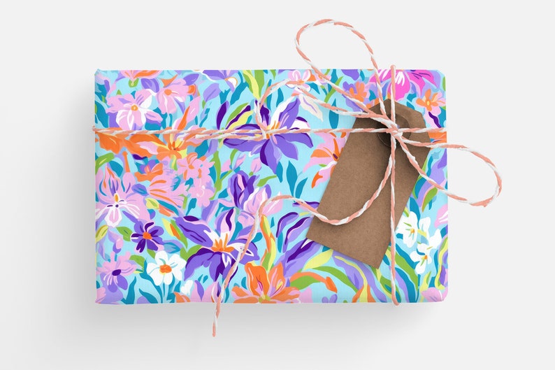 May include: A gift box wrapped in blue floral patterned paper with a brown gift tag tied with pink and white twine.