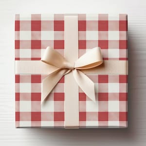 May include: A square gift box wrapped in red and white checkered paper. A cream-colored ribbon and bow are tied around the box. The bow is centered on the top of the box, with the ribbon crossing the top and bottom.