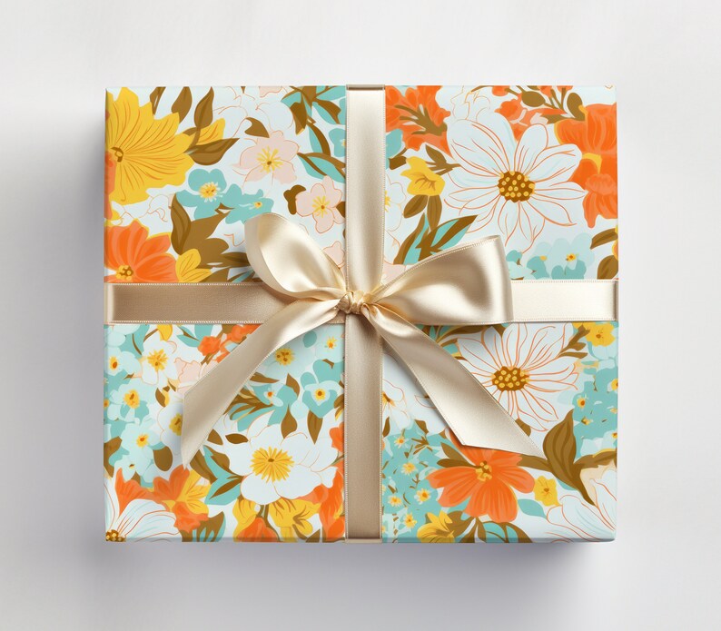 May include: A gift box wrapped in floral patterned paper with a light brown satin ribbon tied in a bow. The paper features a variety of flowers in shades of orange, yellow, blue, and white on a light blue background.