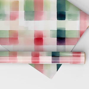 May include: Two rolls of wrapping paper with a watercolor plaid pattern in shades of pink, green, and white.