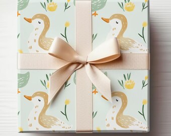 Puede incluir: Una caja de regalo envuelta en papel de regalo azul claro con un patrón de patos y flores amarillas. La caja está atada con una cinta de satén beige.