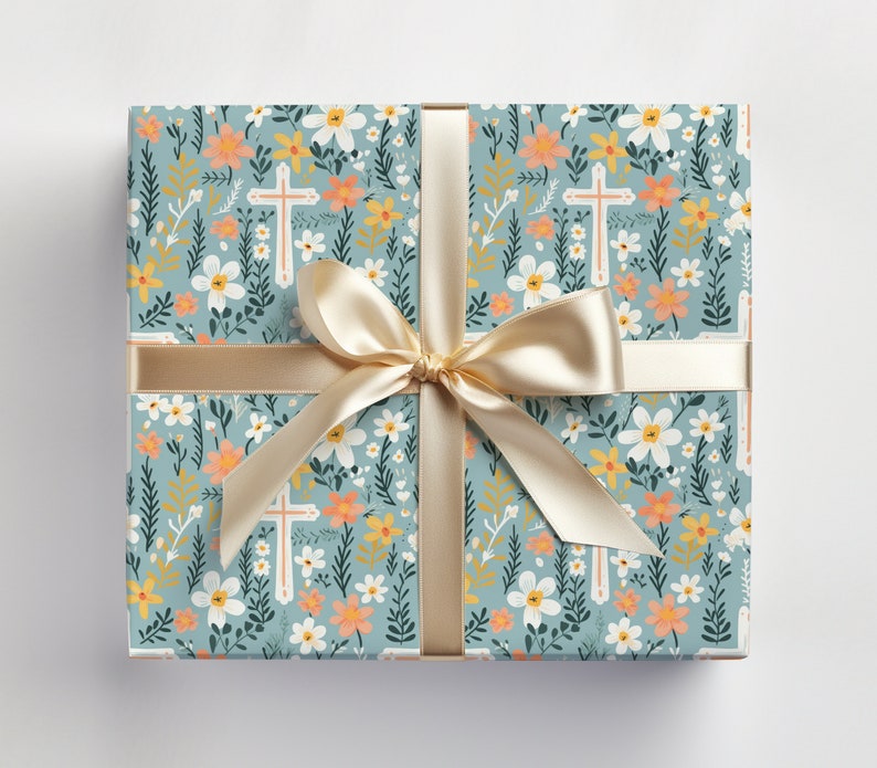 May include: A blue gift wrap with a floral pattern featuring white flowers, green leaves, and orange and yellow accents. The pattern also includes white crosses. The gift wrap is tied with a gold ribbon.