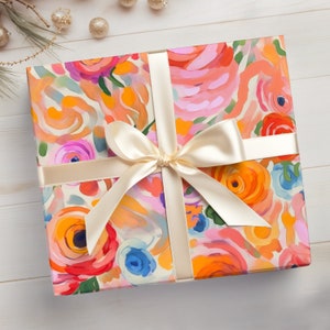 May include: A gift wrapped in colorful floral patterned wrapping paper with a white satin ribbon tied in a bow.