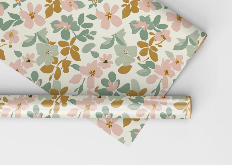 Op de afbeelding: Een rol cadeaupapier met een bloemenpatroon. Het papier heeft roze, groene en gouden bloemen op een cr&egrave;mekleurige achtergrond.