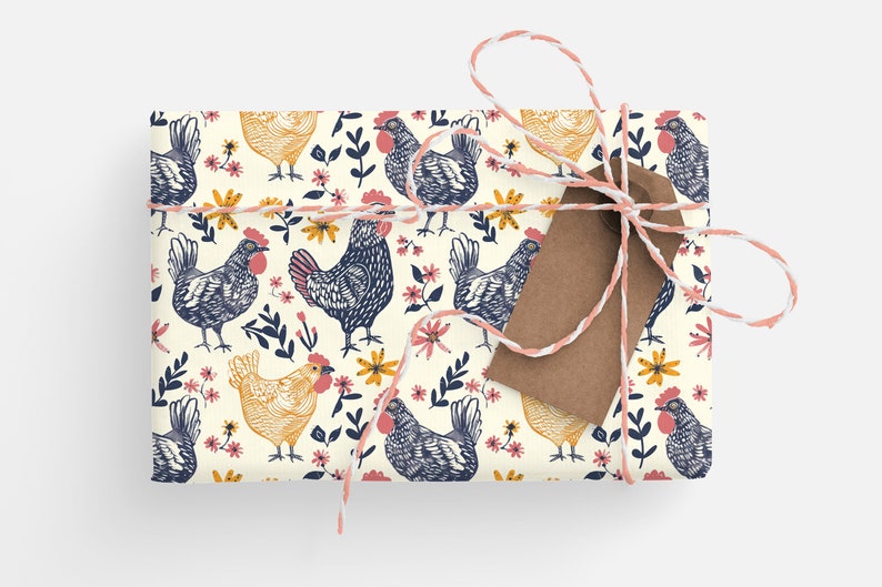 Puede incluir: Un regalo envuelto en papel blanco con un patr&oacute;n repetitivo de pollos azules y amarillos y flores rosas. El regalo est&aacute; atado con un cordel blanco y rosa y tiene una etiqueta de regalo marr&oacute;n.