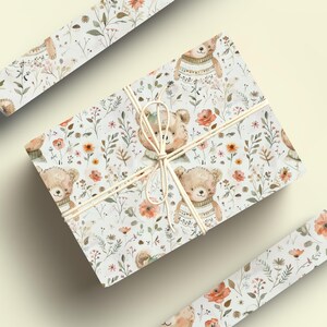 May include: Gift wrap featuring a white background with a repeating pattern of brown bears wearing sweaters, orange flowers, and green leaves.
