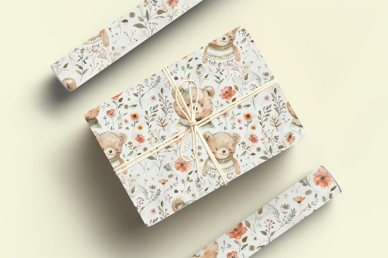 May include: Gift wrap featuring a white background with a repeating pattern of brown bears wearing sweaters, orange flowers, and green leaves.