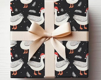 May include: A wrapped gift with a black background featuring a pattern of white geese wearing Santa hats. The geese have gray wings and orange feet. The gift is tied with a beige ribbon and bow.