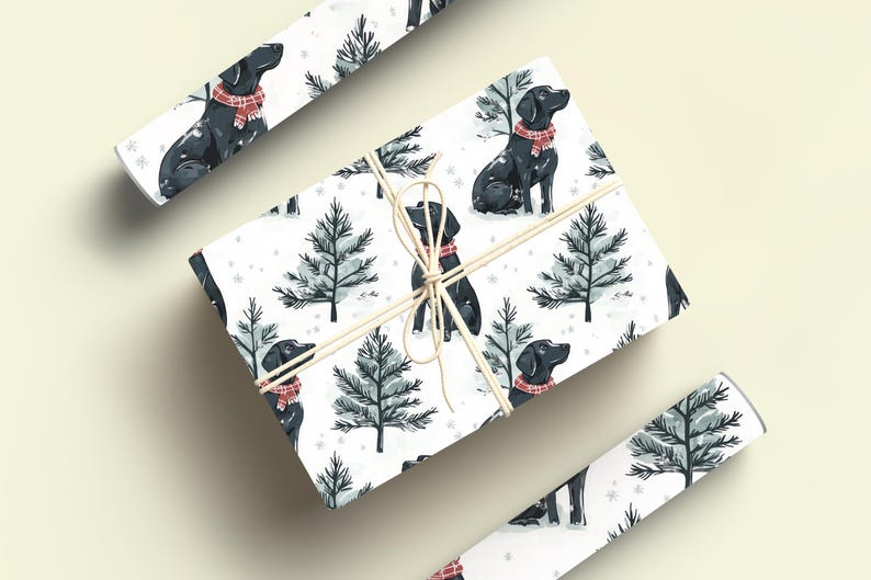 K&ouml;nnte beinhalten: Wei&szlig;es Geschenkpapier mit einem sich wiederholenden Muster aus schwarzen Labradoren mit roten Schottenkaro-Schals und stilisierten Tannen. Das verpackte Geschenk ist mit Bindfaden gebunden, und zwei Rollen passenden Papiers sind ebenfalls sichtbar.