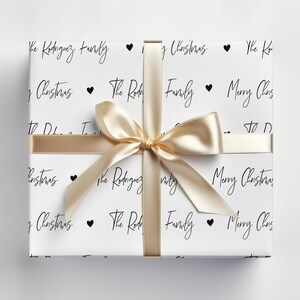 May include: White wrapping paper with a gold ribbon and black text that says "The Rodriguez Family" and "Merry Christmas".