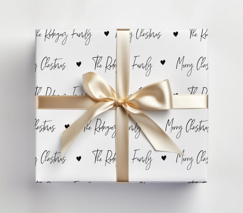 May include: White wrapping paper with a gold ribbon and black text that says "The Rodriguez Family" and "Merry Christmas".