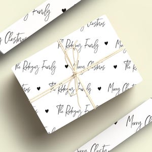 May include: White wrapping paper with a repeating pattern of black hearts and the text "The Rodriguez Family" and "Merry Christmas".