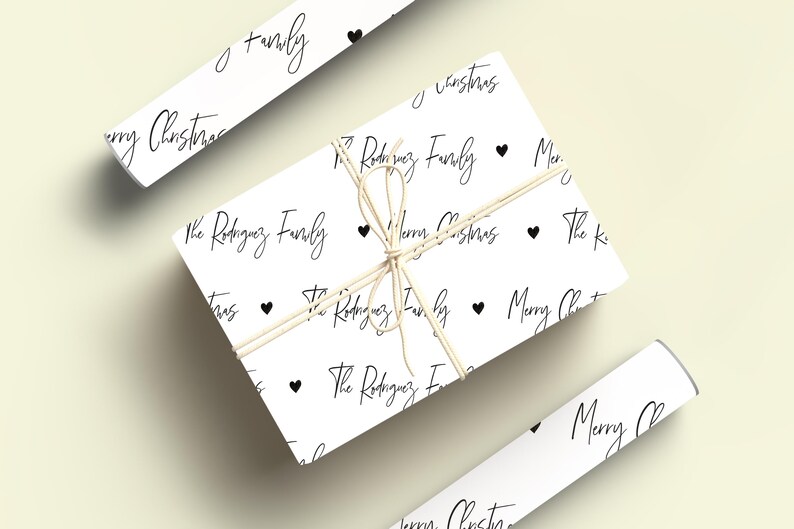 May include: White wrapping paper with a repeating pattern of black hearts and the text "The Rodriguez Family" and "Merry Christmas".
