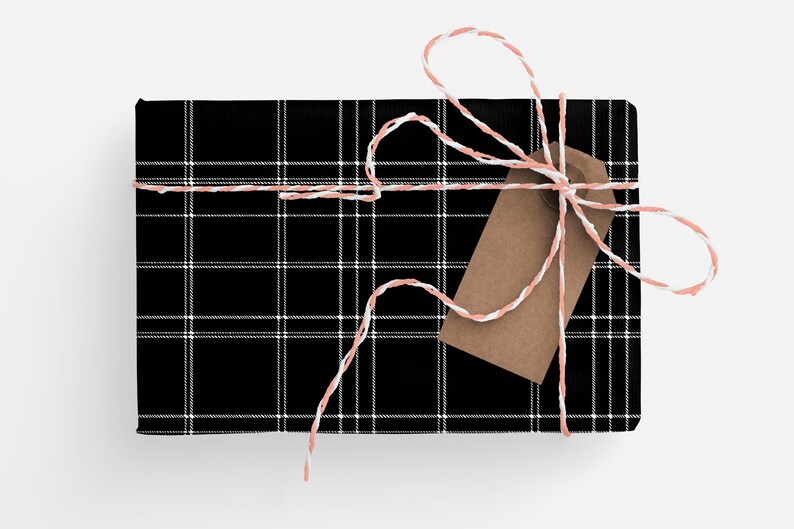 May include: A black and white plaid gift box tied with a white and pink twine bow. A brown gift tag is attached to the bow.