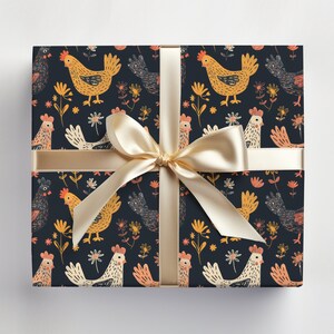 May include: A gift box wrapped in dark blue wrapping paper with a repeating pattern of yellow chickens and flowers. A gold ribbon is tied around the box with a bow.