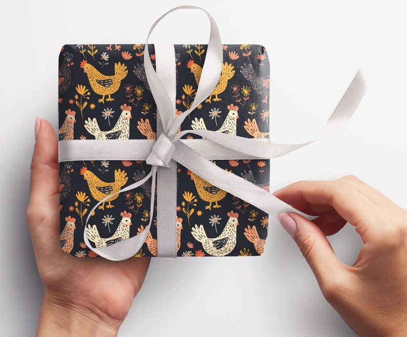 May include: A gift box wrapped in black and white wrapping paper with a pattern of colorful chickens and flowers. The box is tied with a white ribbon.