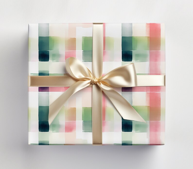 May include: A white gift box with a watercolor plaid pattern in shades of green, pink, and brown. The box is tied with a gold satin ribbon.