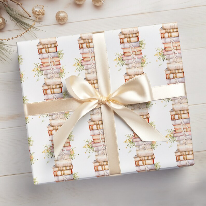 May include: A white gift wrap with a repeating pattern of stacks of books with floral accents. The gift wrap is tied with a cream-colored ribbon with a bow.