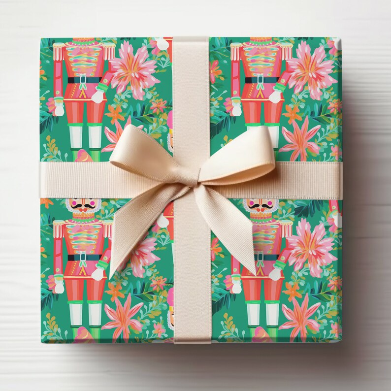 May include: A gift wrapped in green and pink wrapping paper with a pattern of nutcracker soldiers and flowers. The gift is tied with a beige ribbon.