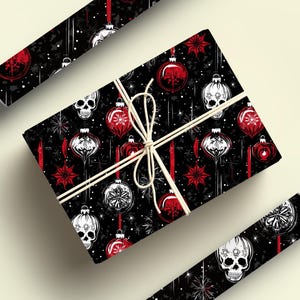 May include: Black and white skull Christmas baubles with red accents on a black background. The wrapping paper features a repeating pattern of the baubles and stars.