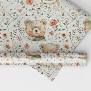May include: White wrapping paper with a repeating pattern of brown teddy bears wearing sweaters, orange flowers, and green leaves.
