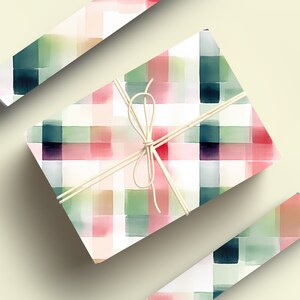 May include: A gift wrapped in white paper with a watercolor plaid pattern in shades of pink, green, and blue. The gift is tied with a natural twine bow.